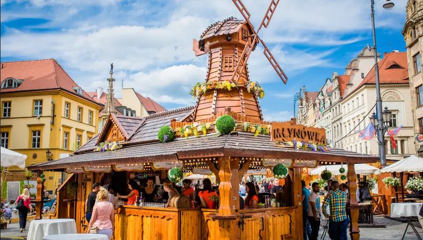 Jarmark Świętojański we Wrocławiu. Na zdjęciu widać drewniany wiatrak i jedno ze stoisko for. Pianoforte Agencja Artystyczna - www.jarmarkswietojanski.com Jarmark Świętojański we Wrocławiu. Na zdjęciu widać drewniany wiatrak i jedno ze stoisk